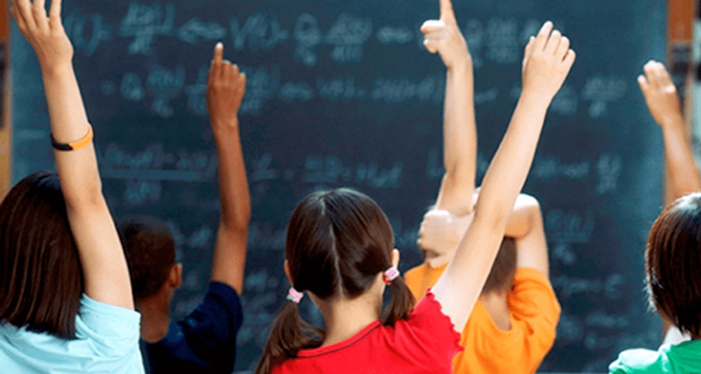 Children rasing their hands in class