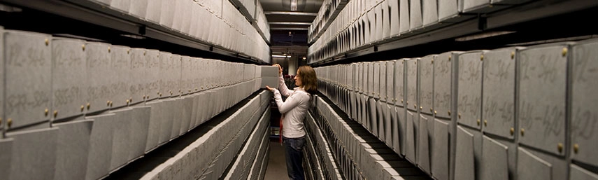 woman removing a file from a corridor of archives