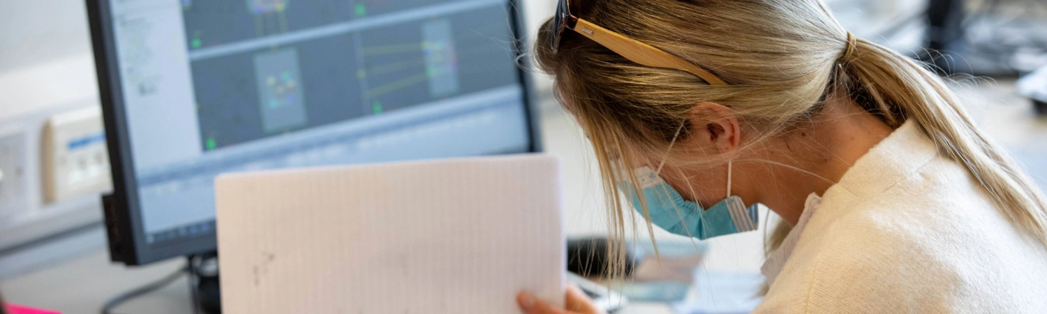 A student studying in front of a monitor wearing a face covering