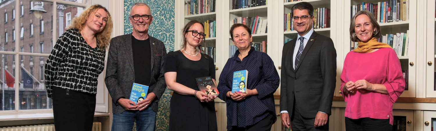 A group of people gathered in the Centre's board room, holding books in the hands.