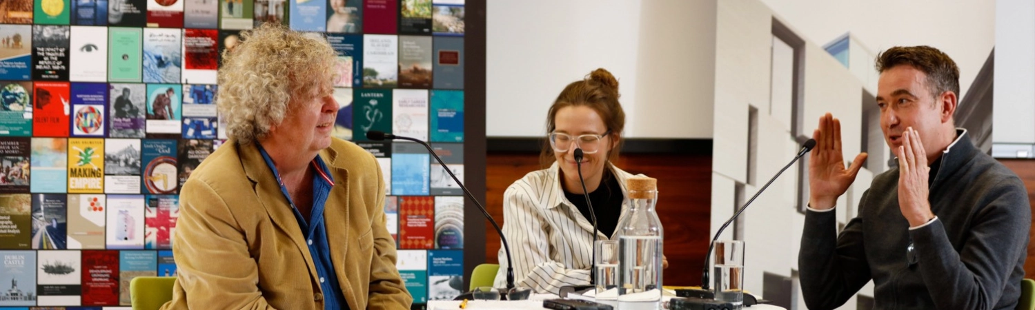 Three people speaking around table with microphones