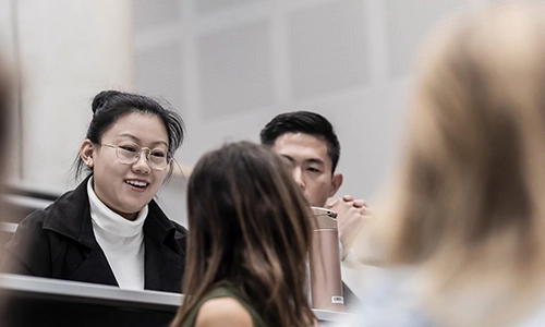 Three students chatting in lecture seats
