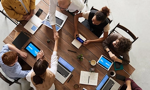 Aerial view of people with laptops sitting around a rectangular table