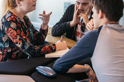 Three students sitting around a table in discussion