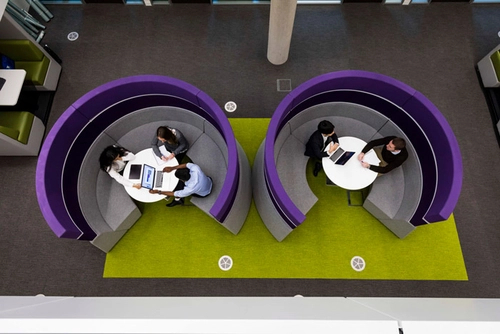 Two sets of people having a company meetings at 2 tables viewed from above