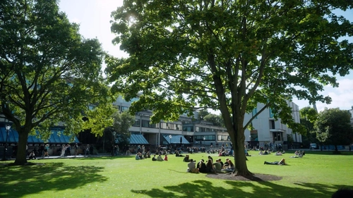 Still of students sitting outside the arts building