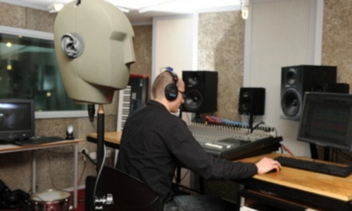 A researcher wearing headphones working on a desktop