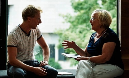 A young man and an elderly woman chatting in the frame of a window