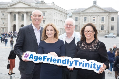 Four people posing with TCD age friendly action banner at outside building
