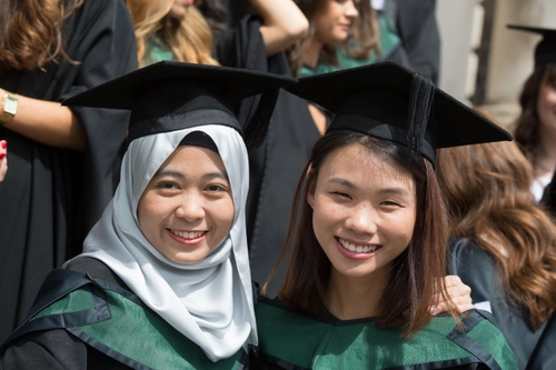 Two Asian students celebrating graduating at Trinity College Dublin