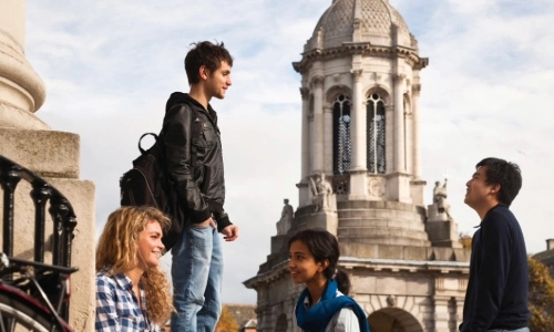 Three students sitting in Front Square with the Bell Tower in the background of the picture