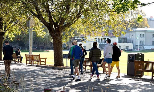 Students walking past cricket pitch