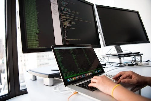 Four computers screens with code on them.