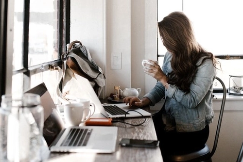 Woman drinking coffee at laptop