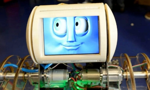 A robot which has a screen with a face on it and wires underneath the screen to the body of the robot