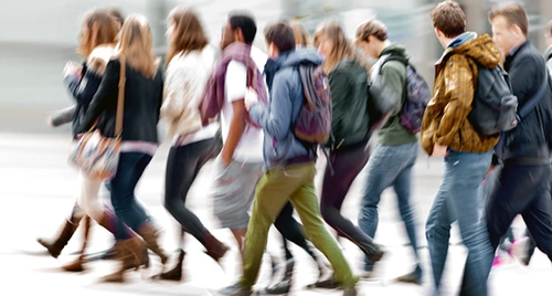 Group of college students walking through Trinity College campus.