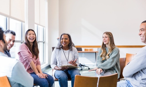 A group of people sitting in a circle talk and smile