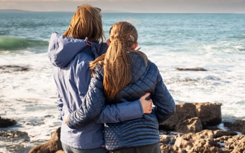 Mother and daughter look out to sea