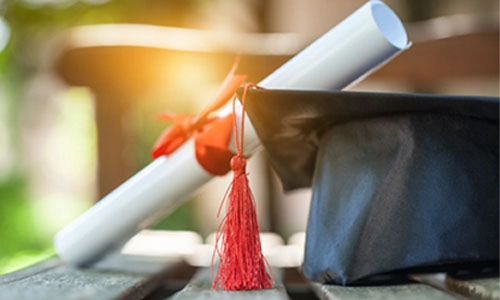 Graduation hat and diploma on wooden background