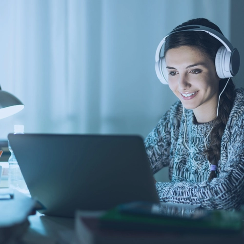 Woman wearing headphones and looking at laptop