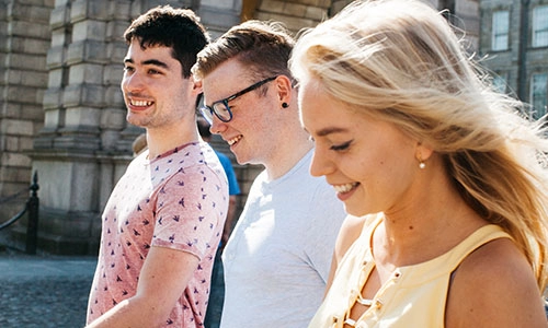 Three students walk through the Trinity College campus