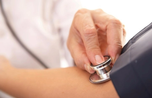 A doctor placing a Stethoscope on the inside of a patient's elbow