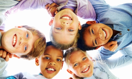 Five children in a circle, looking down at the camera