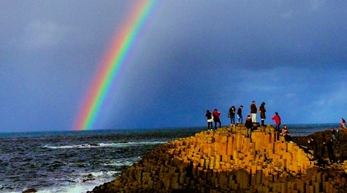 Image of Trinity College students at the Giant's causeway with a rainbow in the background.