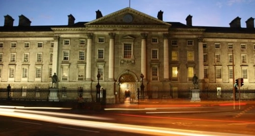 An image of TCD College Green in the evening with traffic passing by