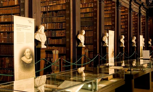A picture of a Old library in Trinity College Dublin containing many aisles of old books and busts of famous scholars