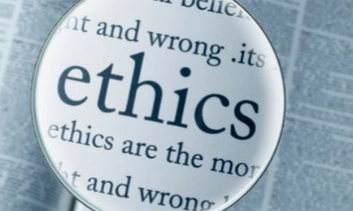 A photo of a page being inspected by a magnifying glass and the word ethics being magnified over the other words on the page