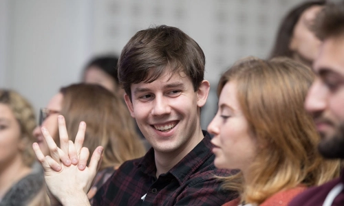male and female student chatting to each other in lecture theatre