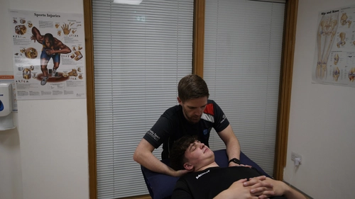Trinity Sport physiotherapist Ciaran working with a client in his office