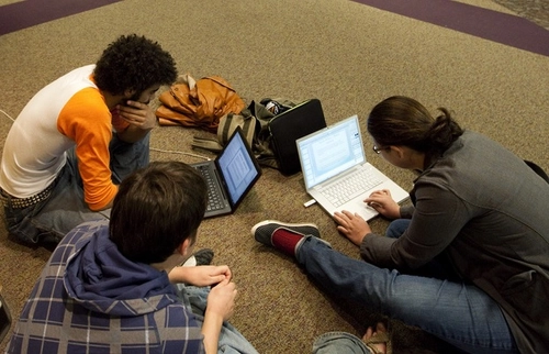 Students huddling around a computer at a meeting