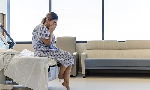 Anxious patient sitting at end of hospital bed