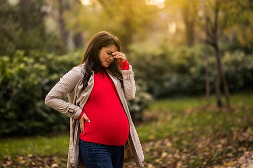 Pregnant woman holding hand to head