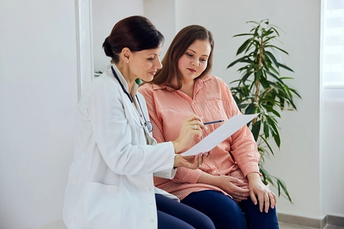 Female doc holding a file and speaking to a pregnant woman