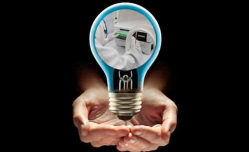 two palms holding lightbulb with a scientist and machinery at the centre