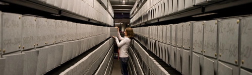 woman removing a file from a corridor of archives