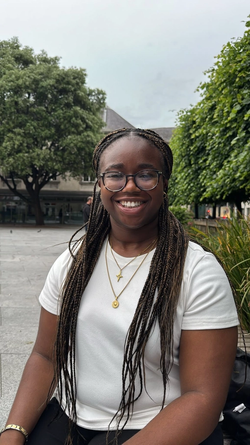 Student with long brown/black hair in braids wearing glasses.