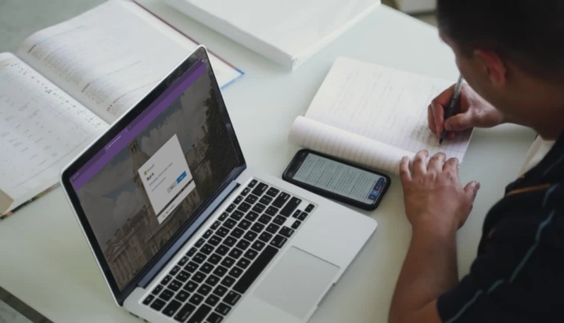 Student working at laptop, taking notes.