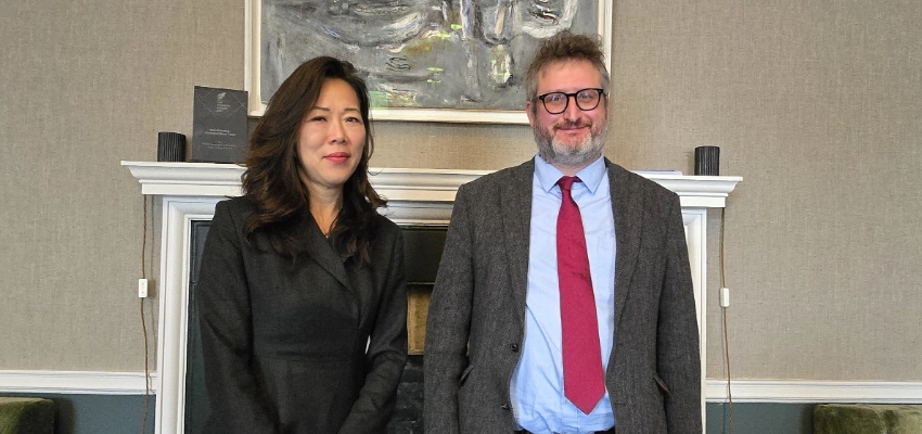 Professor Nathan Hill and H.E. Ms Jooyeon Ellen Kang stand together in a formal reception room, in front of a white fireplace and a large abstract painting