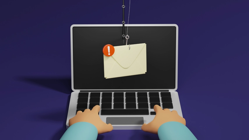 Hands typing on laptop with a phishing email on the screen.