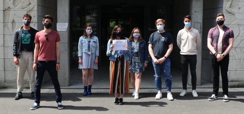 members from Trinity College Institute of Neuroscience stand outside the Lloyd Building, distanced and wearing masks, showing off their new My Green Labs certification