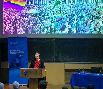 Professor Aileen Kavanagh speaking at a podium with a large screen behind