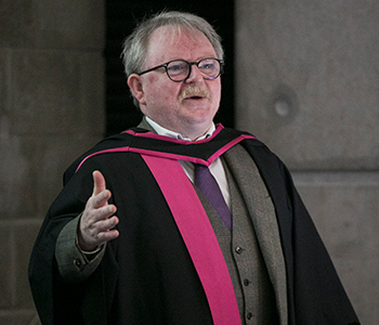 Professor John Divers in robes standing at a lecture podium