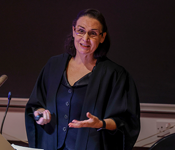 Professor Sharyn O'Halloran speaking at a lecture podium