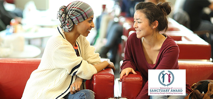 Two female student chatting in red leather chairs