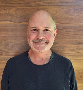 Prof Van Gosse smiling against a wooden backdrop