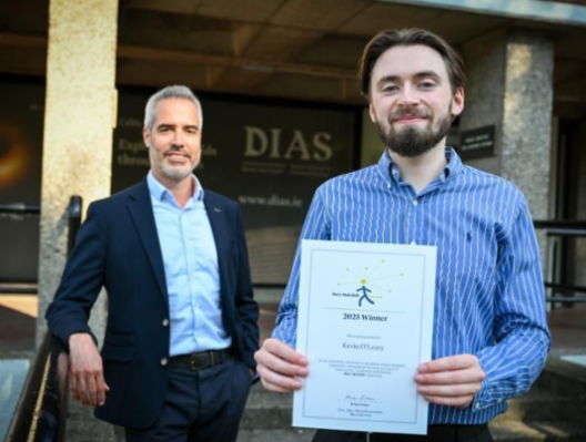 conor holding certificate outside building beside presenter